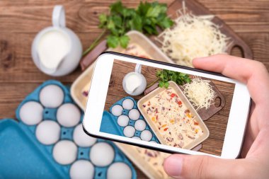 Eller fotoğraf omlet jambon ve peynir ile smartphone ile pişirme formunda alarak.