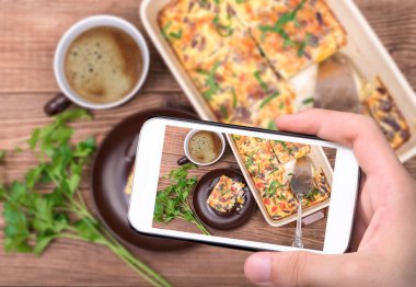 Eller fotoğraf omlet jambon ve peynir ile smartphone ile pişirme formunda alarak.