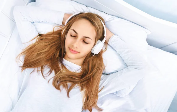 Girl in bed with a headphones on listening to the music — Stock Photo, Image