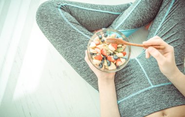 Genç kadın dinlenme ve bir egzersiz yaptıktan sonra bir meyve salatası yemek. 