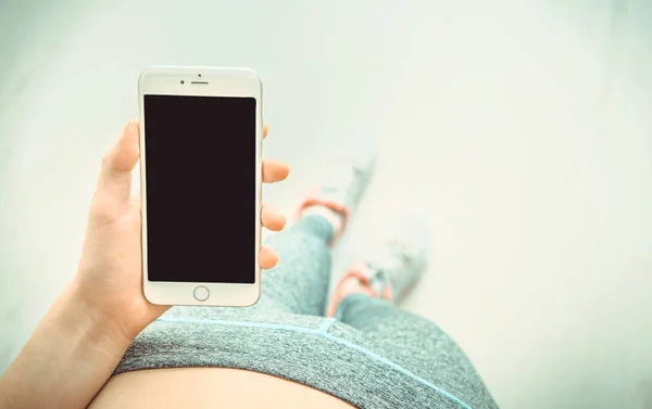 Junge Frau bedient sich nach dem Training einer Fitness-App auf ihrem Smartphone. — Stockfoto