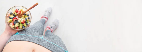 Young woman is eating a healthy fruit salad after a workout. — Stock Photo, Image