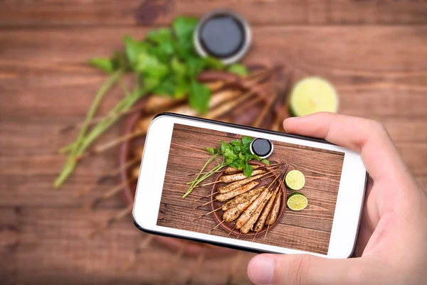 Handen nemen foto zelfgemaakte Thaise kip saté met smartphone. — Stockfoto