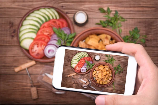 Manos tomando carne fotográfica estofada con papas en tazón con smartphone . —  Fotos de Stock