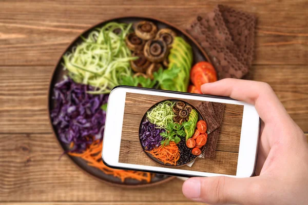 Mãos tirando foto Buda tigela de legumes misturados com smartphone . — Fotografia de Stock