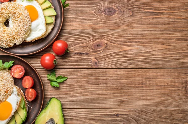 Bagel with avocado and egg on the wooden background. — Stock Photo, Image