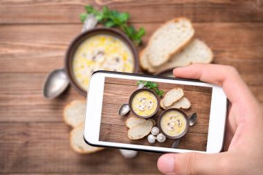 Foto mantar çorbası ile smartphone alarak eller.