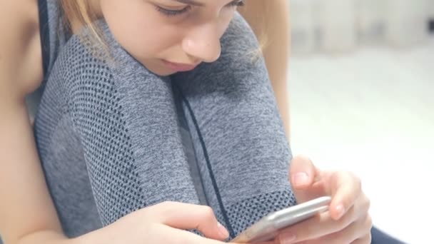 Jovem está usando um aplicativo de fitness em seu smartphone depois de um treino . — Vídeo de Stock