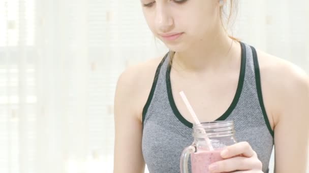 Jonge vrouw is een smoothies te drinken en met behulp van een fitness-app op haar tablet na een training. — Stockvideo