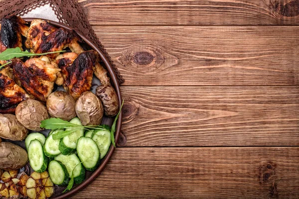 Ailes de poulet avec pommes de terre cuites au four sur fond en bois . — Photo