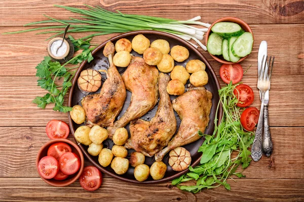 Patas de pollo con patatas y verduras al horno sobre fondo de madera . —  Fotos de Stock