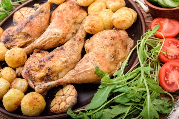 Nogi kurczaka z pieczonymi ziemniakami i warzywami na podłoże drewniane. — Zdjęcie stockowe