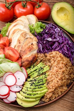 Quinoa, tavuk, avokado ve sebze ile sağlıklı salata kasesi.