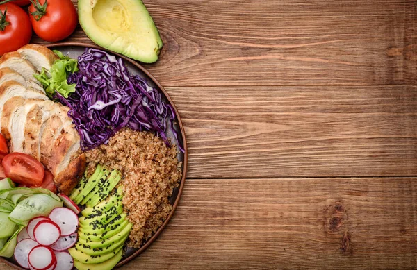 Healthy salad bowl with quinoa, chicken, avocado and vegetables.