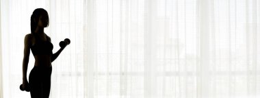 Pencere arka plan üzerinde dumbbells ile çalışan kadın silüeti .