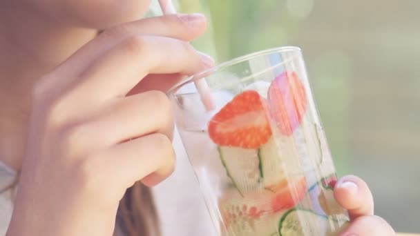 Mujer joven bebiendo agua de desintoxicación de pepino y fresa  . — Vídeos de Stock