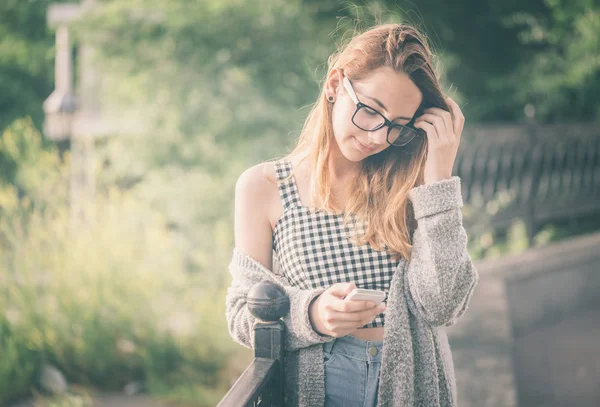 Fille à l'aide d'un téléphone portable à l'extérieur . — Photo