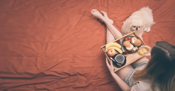 La jeune femme est couchée au lit et prend un petit déjeuner sain . — Photo