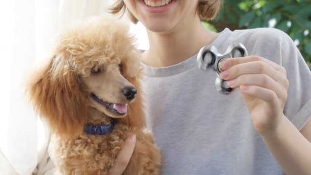 Young woman with her dog plays and twists the hand spinner. — Stock Video