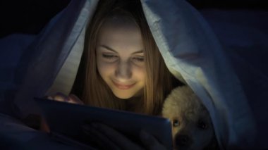 Cinemagraph - köpeğini tablet ile yatakta kızla. Hareketli fotoğraf.