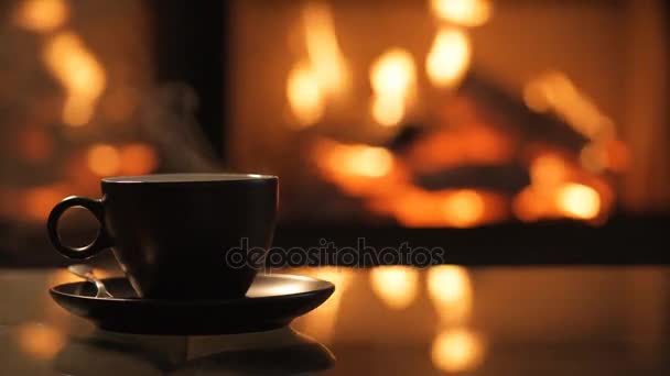 Cap of coffee on table in front of burning fireplace. — Stock Video