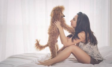 Genç bir kadın ile bir kaniş köpek yatakta dinleniyor.