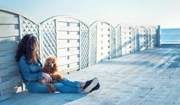 Femme avec son chien sur la terrasse en bois sur la plage de la mer  . — Photo