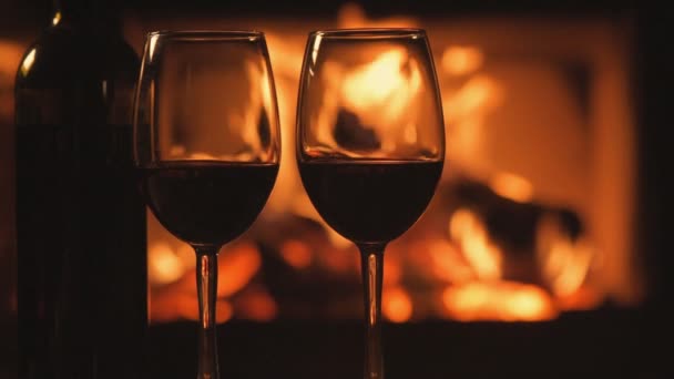 Cinemagraph - Bottle and two red wine  wineglasses over fireplace background. — Stock Video