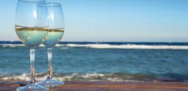 İki beyaz şarap kadehlerin deniz arka plan üzerinde. Sahilde tatil tropikal.