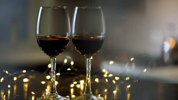 Δύο Wineglasses Του Κόκκινου Κρασιού Διακόσμηση Γιρλάντες Από Φώτα — Αρχείο Βίντεο