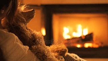 Genç kadın ile köpek şöminenin yanında oturan.