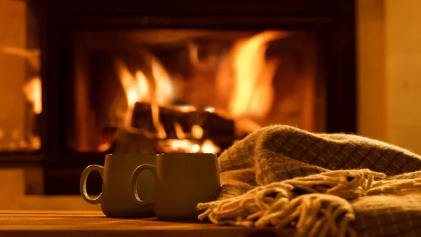 Steam from a cups with a hot cocoa on the fireplace background.