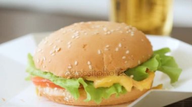 Sulu biftek hamburger yemek tepesinde susam tohumu çörek üzerinde peynir ve taze sebze.