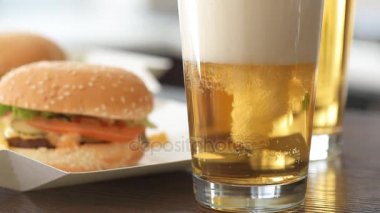 Cinemagraph - cam içine dökme light bira. Taze sebze ve bira gözlük ile iki hamburger. Hareketli fotoğraf.