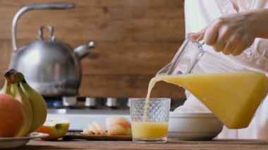Genç kadın portakal suyu bir bardak dökme. Kahvaltı. 