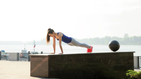 Молода жінка займається спортивною підготовкою, вона робить віджимання на вулиці Ліцензійні Стокові Фото