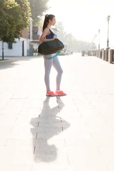 Mujer atlética joven de pie con una bolsa de deporte en el hombro Imágenes de stock libres de derechos