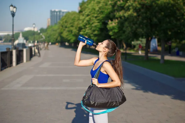 Junge athletische Frau trinkt nach dem Training Wasser aus einer Flasche Stockbild