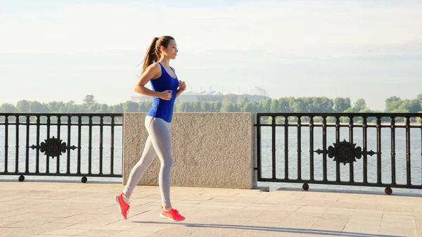 Mujer atlética joven corriendo a lo largo del paseo marítimo Imagen de archivo