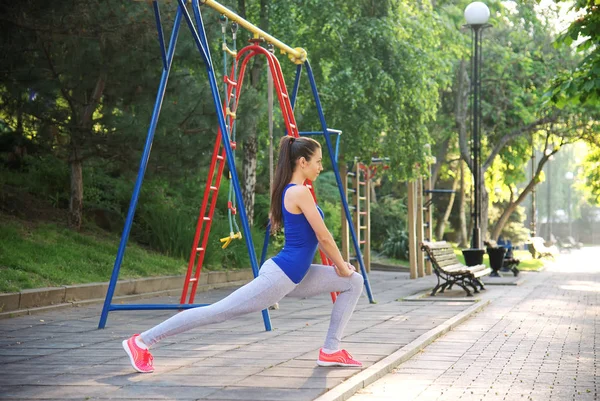 Junge athletische Frau beim Ausfallschritt auf einem Sportplatz lizenzfreie Stockbilder