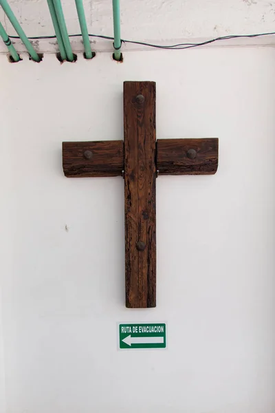 Crucifix with sign of evacuation route on concrete wall Stock Picture