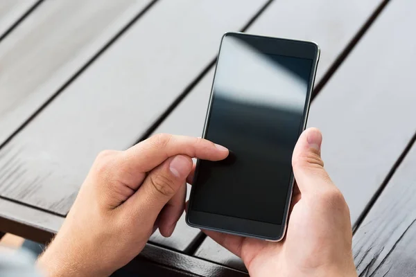 Man holding smart mobile phone on wooden table background — Stock Photo, Image