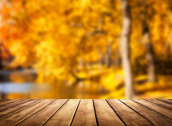 Dřevěný stůl top na rozmazané podzimní pozadí — Stock fotografie