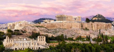 Atina Panoraması ve Akropolis tepesi dramatik günbatımında, Yunanistan. Atina Akropolü, Atina 'nın yukarısındaki kayalık bir çıkıntıda yer alıyor ve aralarında en ünlüsü Parthenon olmak üzere çok sayıda antik binanın kalıntılarını barındırıyor..