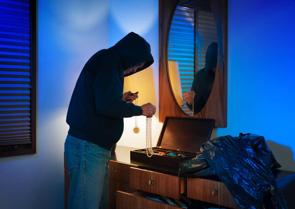 Hooded home burglar taking jewelery