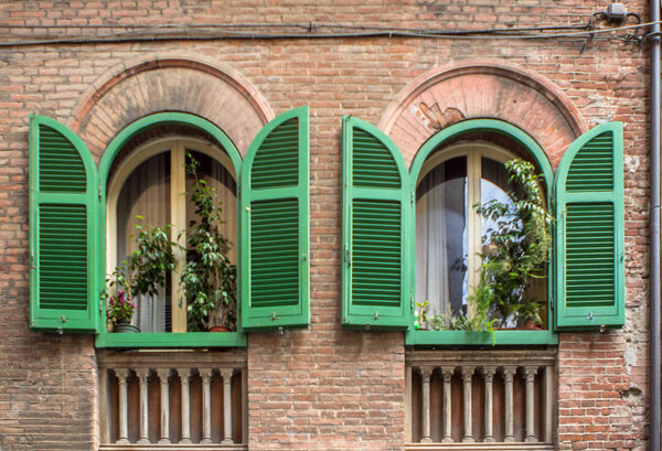 Old, brick house with opened green shutters in Pisa, Tuscany, Italy