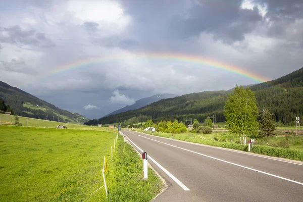 Arco-íris acima da estrada e montanhas — Fotografia de Stock