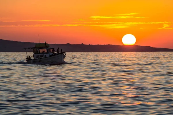 Sunset over sea with silhouette of small boat — Stock Photo, Image