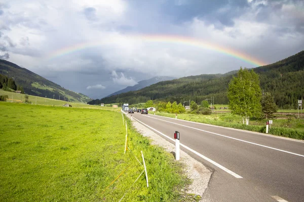 Regenbogen über Straße und Bergen — Stockfoto