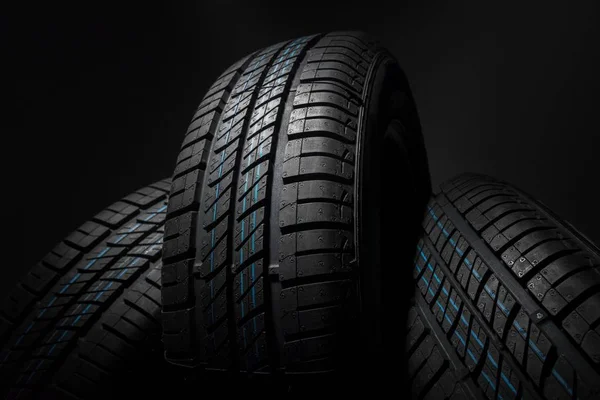 New and unused car tires against dark background — Stock Photo, Image